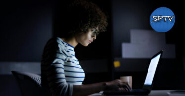 A young dark skinned girl working with her laptop at night